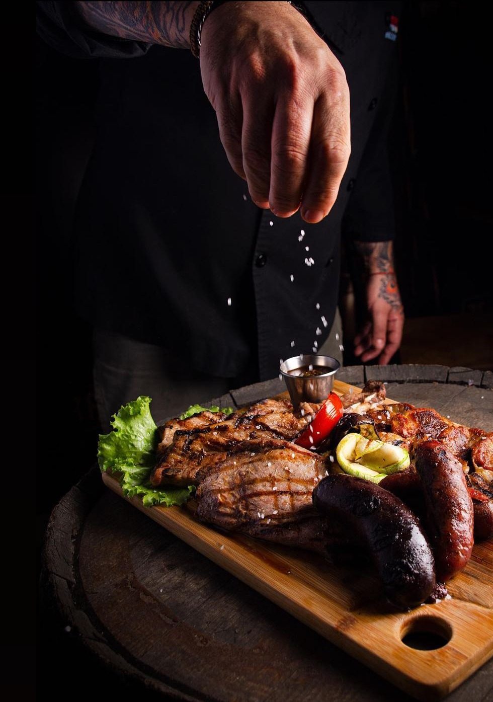 Mano del parrillero salando la tabla de parrillada