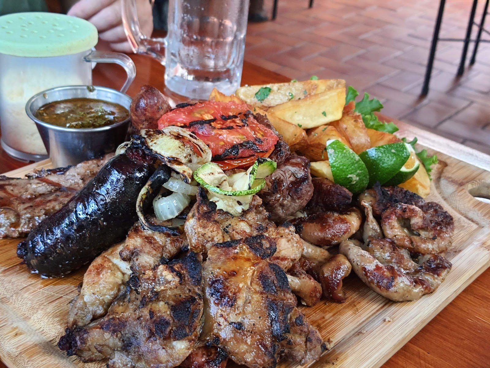 Tabla de parrillada con papas y cerveza en la mesa