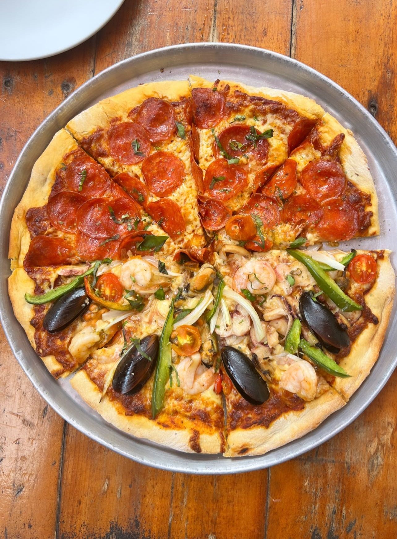Pizza mitad pepperoni y mitad mariscos en la mesa del deck